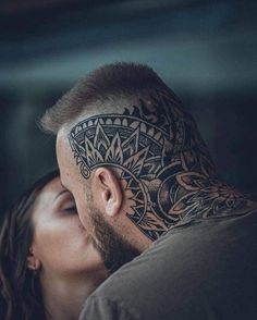 a man and woman kissing each other with tattoos on their foreheads behind the heads