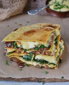 a close up of a sandwich on a piece of paper with other food items in the background