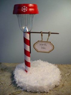 a red and white pole sitting on top of a pile of snow next to a sign that reads north pole street light made out of solar light from dollar store