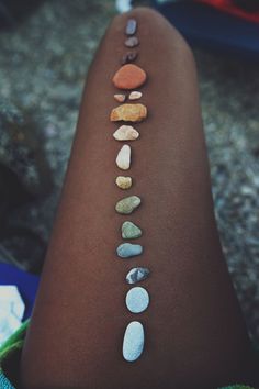 a woman's arm with different colored stones on the back of her leg, all lined up in a row