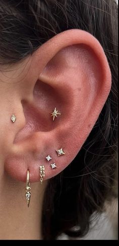 a woman wearing three different ear piercings on her left ear and one with stars