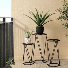 three plant stands with plants in them on a balcony