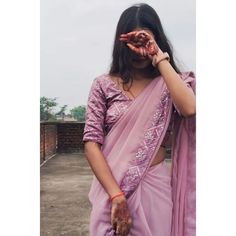 a woman in a pink sari holding her hands up to her face