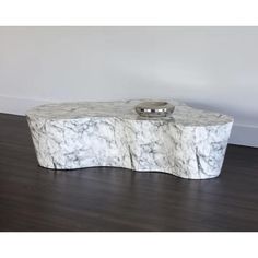 a white marble table with a bowl on it's top and a wooden floor