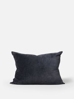 a black pillow sitting on top of a white wall