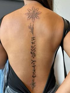 the back of a woman's tattoo with flowers on her upper and lower back