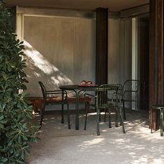 a table and four chairs sitting under a tree