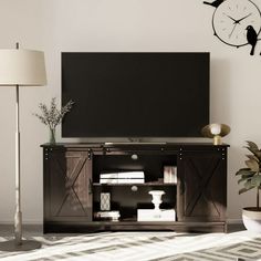 a flat screen tv sitting on top of a wooden entertainment center next to a lamp