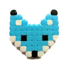 a blue and white brooch that looks like a pixel head with two black eyes