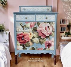 a painted dresser with flowers on it in a pink and blue room next to a bed