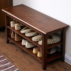 a wooden bench with several pairs of slippers on it and a rug in the corner