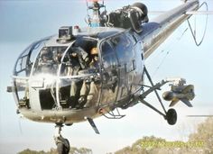 a man hanging from the side of a helicopter