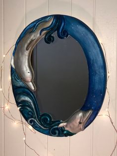 a blue and white circular mirror hanging on the wall next to a christmas wreath with lights