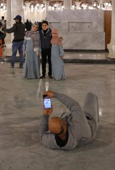 a man laying on the ground taking a selfie with his cell phone in front of him