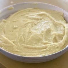 a white bowl filled with batter sitting on top of a counter next to a knife