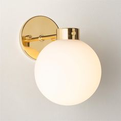 a wall light with a white glass ball on the side and a gold plated arm