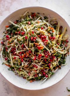 a white bowl filled with shredded vegetables and pomegranates on top of a table