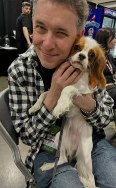 a man sitting in a chair holding a small brown and white dog on his lap