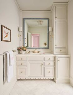 a large bathroom with white cabinets and pink door on the mirror over the sink is also decorated with flowers