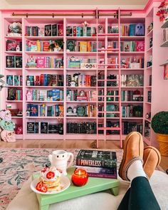 a person sitting on a couch in front of a book shelf filled with books and tea