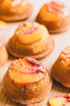 several small pastries on a wooden surface with peaches in the foreground and another one behind them