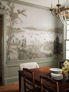 a dining room with a table and chairs in front of a painting on the wall