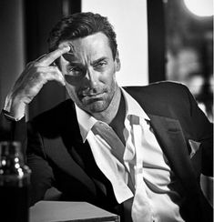 a man in a suit and tie sitting at a table with his hand on his head