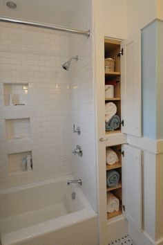 a bathroom with white walls and tile flooring next to a bathtub filled with towels