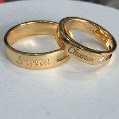 two gold wedding rings sitting on top of a white table with the word sweet written on them