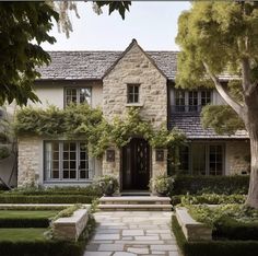 a stone house with hedges and trees around it