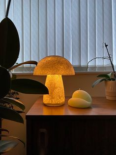 a mushroom shaped lamp sitting on top of a table next to a potted plant