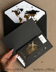 a person holding an envelope with a world map on the front and bottom, in gold foil