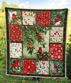 a quilted christmas tree with cardinals and holly leaves on it, hanging in the grass