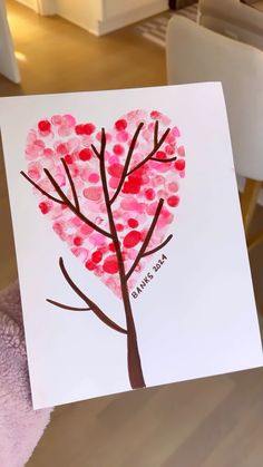 a hand holding up a card with a heart shaped tree on it