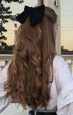 a girl with long hair wearing a black bow in her hair is looking out the window