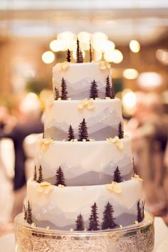 a three tiered cake with pine trees on the top is sitting on a table