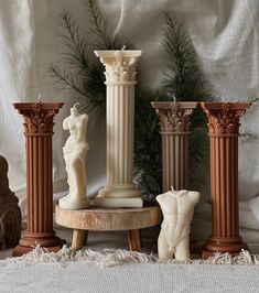 some statues are sitting on pedestals in front of a white background with pine branches