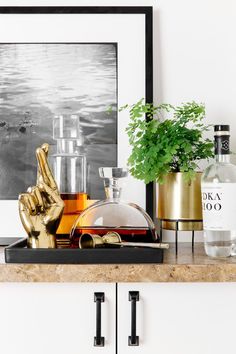 a table topped with bottles and glasses filled with liquid next to a gold hand statue