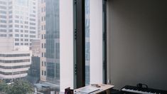 a desk with a keyboard and music equipment in front of a window overlooking the city