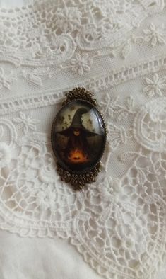 a brooch with an image of a woman sitting on top of a lace tablecloth