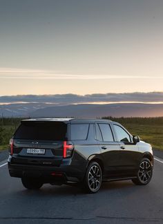 a black suv is driving down the road