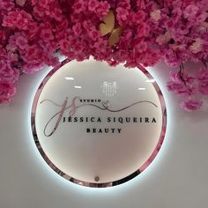 pink flowers are hanging from the ceiling in front of a circular sign that reads, tressica siqueria beauty