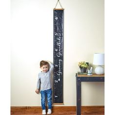 a little boy standing next to a tall ruler