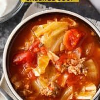 a bowl filled with cabbage and meat soup on top of a table next to a spoon