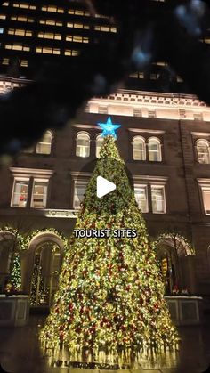 a large christmas tree is lit up in front of a building with lights on it