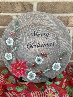 a merry christmas plate with poinsettis and holly on it sitting in front of a brick wall