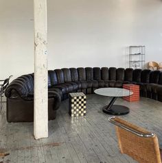 a living room filled with black leather couches next to a dining table and chairs