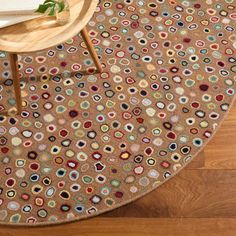 a brown rug with multicolored circles on the floor next to a wooden table