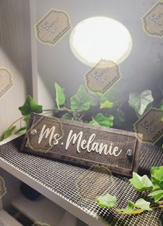 a wooden sign that says ms melanie on top of a table with ivy