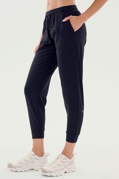 A person is shown wearing SPLITS59's Classic Airweight Jogger in Black and white athletic shoes. The focus is on the side view of the lower body, perfect for a workout. Black Breathable 4-way Stretch Pants, Black 4-way Stretch Yoga Pants For Jogging, Black Activewear With Elastic Waistband And Athletic Fit, Black Athleisure Bottoms With 4-way Stretch, Go-dry Relaxed Fit Sweatpants For Sportswear, Black Go-dry Athleisure Bottoms, Casual Black Yoga Pants With Comfort Stretch, Black Athleisure Bottoms, Comfortable Black Stretch Pants